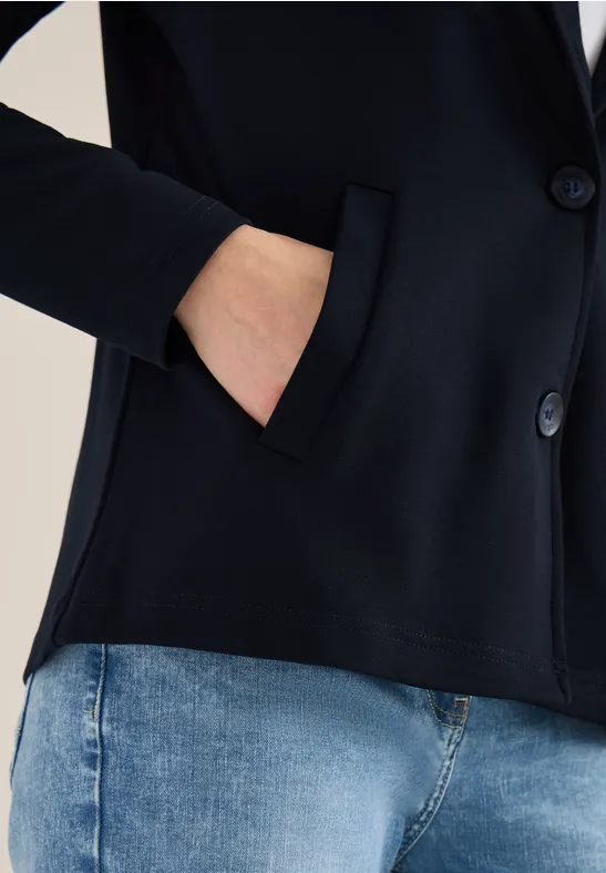 Schwarzer Blazer mit Hand in Seitentasche, kombiniert mit Jeans.