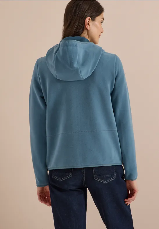Frau von hinten in blauer Kapuzenjacke und Jeans