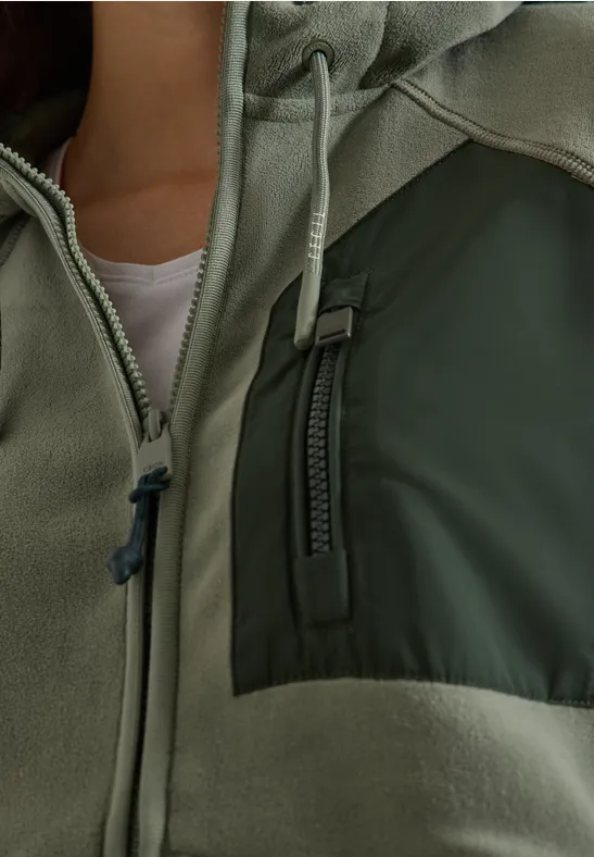 Nahaufnahme einer grünen Jacke mit Reißverschluss und Brusttasche.