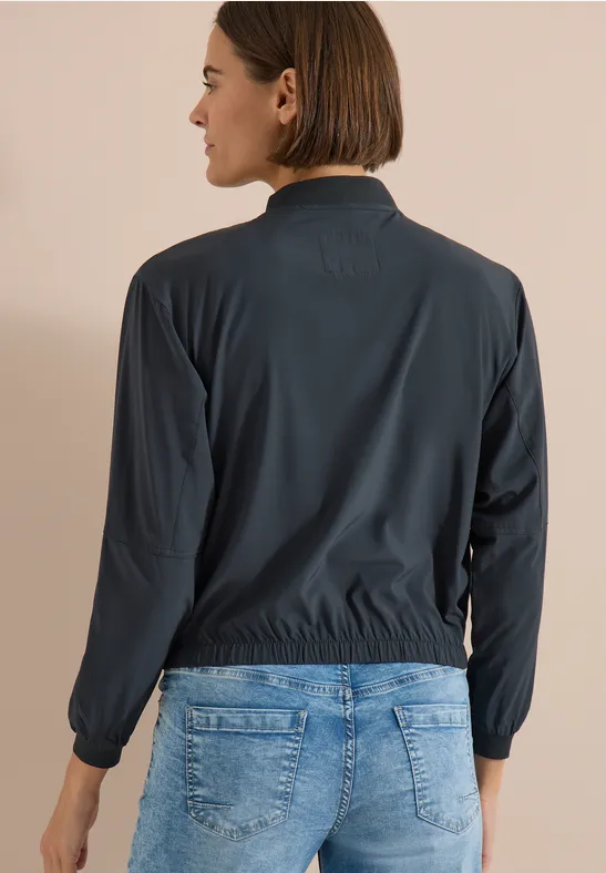 Person mit dem Rücken zur Kamera, dunkle Jacke und blaue Jeans.