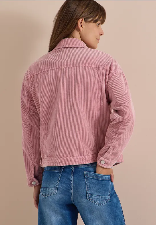 Eine Frau von hinten in rosa Cordjacke und blauer Jeans.