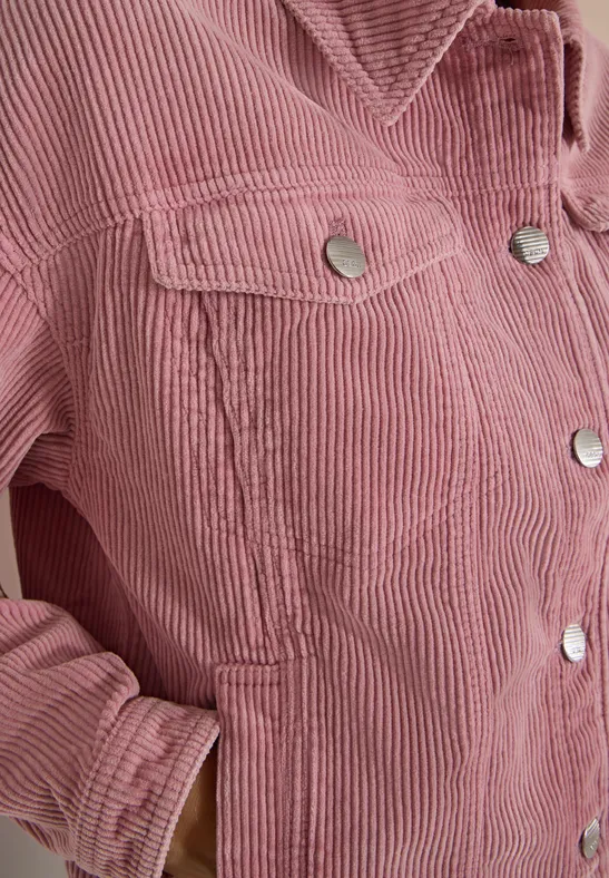 Nahaufnahme einer rosa Cordjacke mit silbernen Druckknöpfen und seitlicher Tasche.