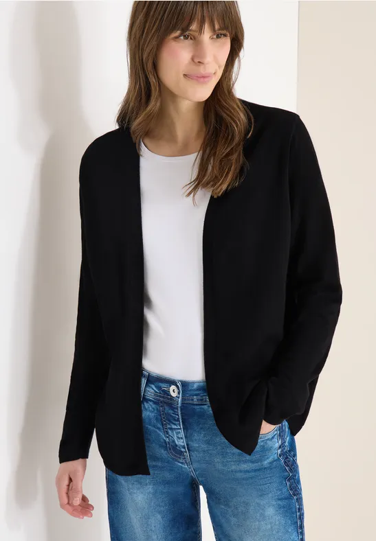 Leichte schwarze Strickjacke offen, mit weißem T-Shirt und blauer Jeans vor weißem Hintergrund.