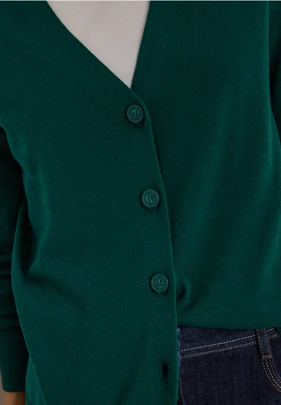 Dunkelgrüner Cardigan mit Knöpfen kombiniert mit dunkelblauer Jeans.