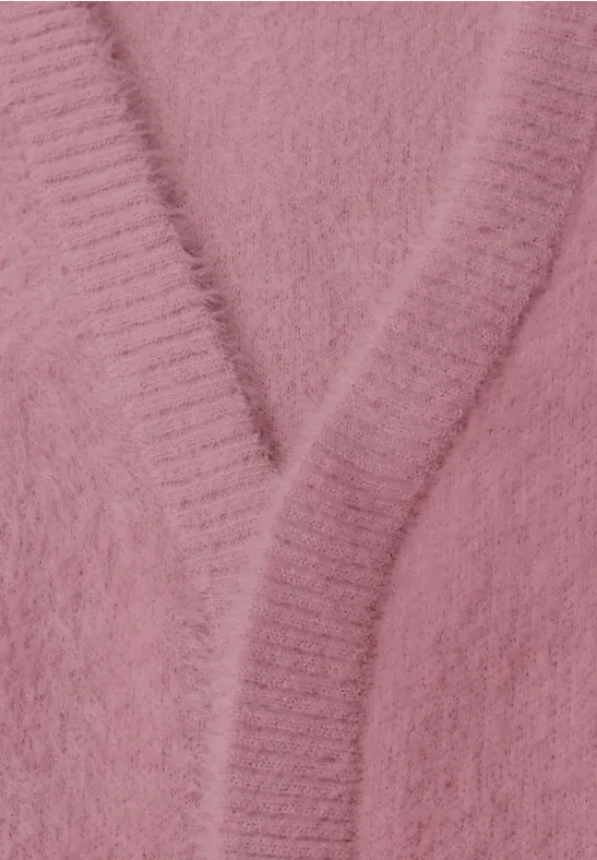 Gros plan d'un cardigan en maille rose duveteuse avec encolure en V.