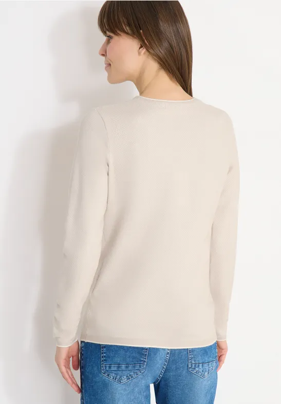 Person blickt von hinten, trägt hellbeigen Pullover und blaue Jeans vor hellem Hintergrund.