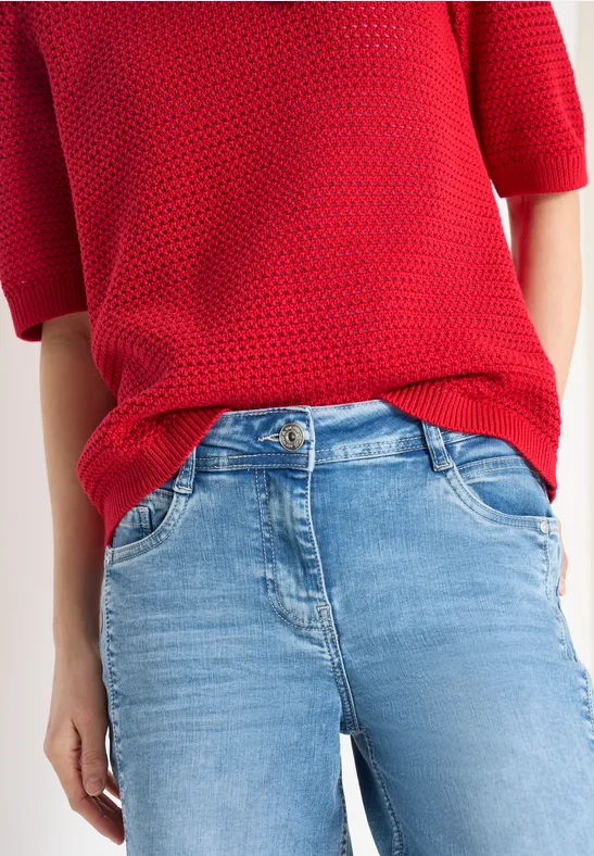 Roter Strickpullover mit hellblauen Jeans, nur der Oberkörper sichtbar