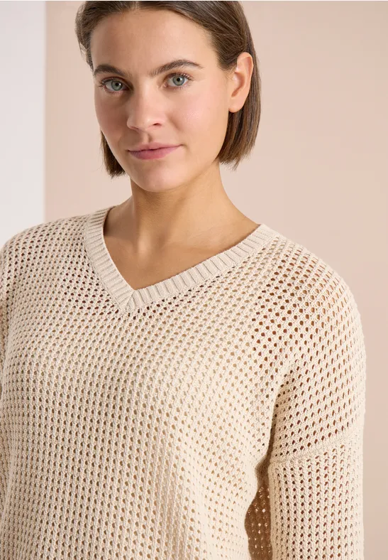Pull beige ajouré en maille filet, coupe ample et col en V.