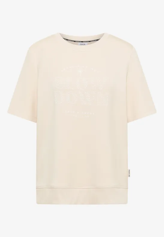 T-shirt beige à coupe ample avec inscription discrète blanche sur le devant.