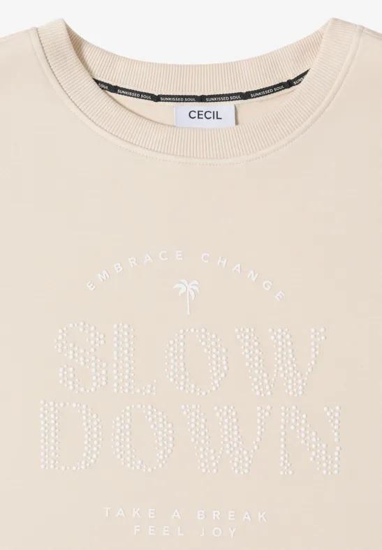T-shirt beige CECIL orné de strass, imprimé "SLOW DOWN" et motif palmier.