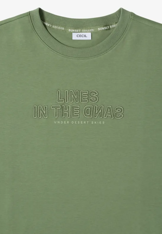 T-shirt olive à manches courtes avec inscription blanche « LINES IN THE SAND2 » et petit texte « UNDER DESERT SKIES ».
