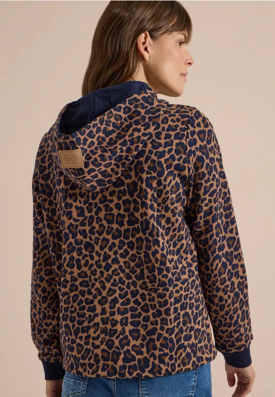 Vue de dos d'une femme portant un gilet à capuche ample au motif léopard brun et noir.