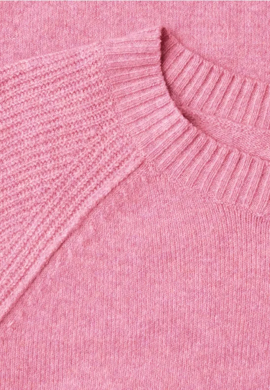 Gros plan d'un pull rose en maille avec col rond et texture délicate.