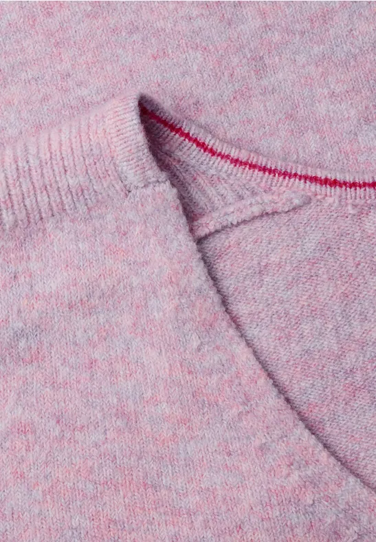 Gros plan d’un pull en maille rose chiné avec couture apparente.