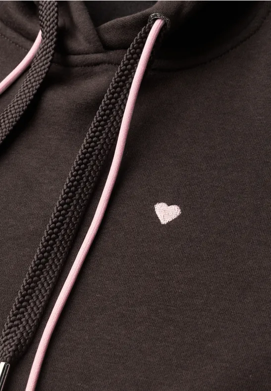 Sweat à capuche noir avec petit cœur blanc sur la poitrine et cordons noirs et roses.