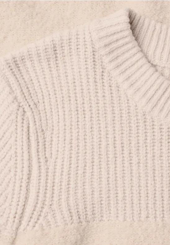 Heller beige gestrickter Pullover mit Rippenmuster.