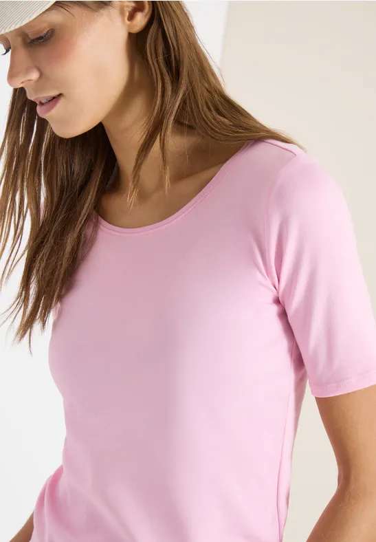 Une personne porte un t-shirt rose clair à manches mi-longues.