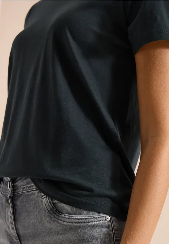 Eine Person trägt ein schwarzes T-Shirt und eine Jeans.