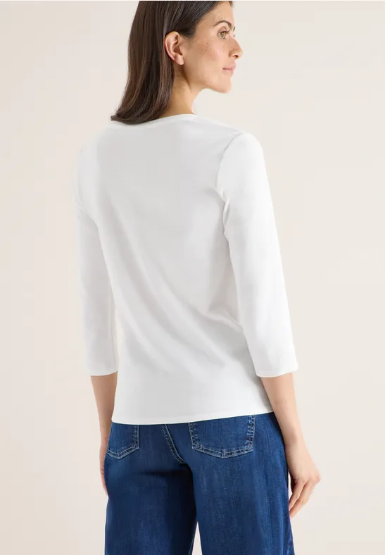 Frau von hinten mit weißem Langarmshirt und blauer Jeans.