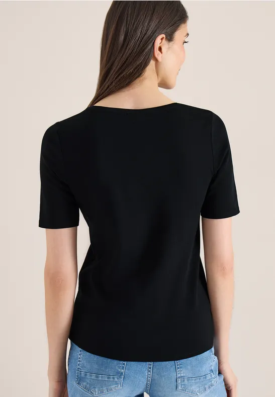 Frau von hinten in schwarzem Kurzarmshirt und blauen Jeans.