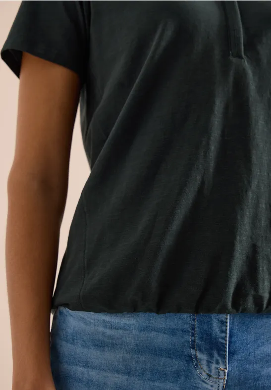 Eine Person trägt ein schwarzes T-Shirt und blaue Jeans.