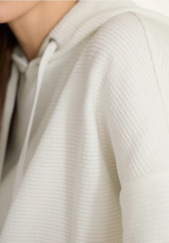 Weißer, strukturierter Hoodie aus Waffelstrick, nahes Detail der Schulter und Kapuze