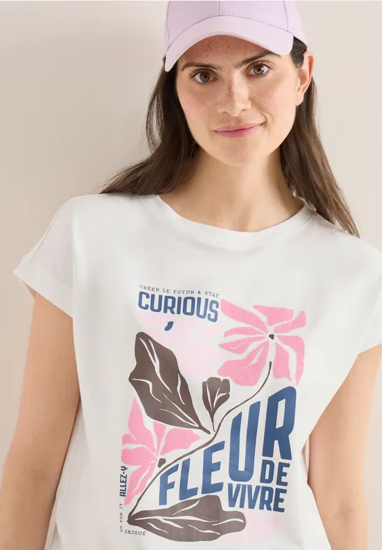 Weißes T-Shirt mit floralem Design und Schriftzug ‚Curious‘ und ‚Fleur de vivre‘.
