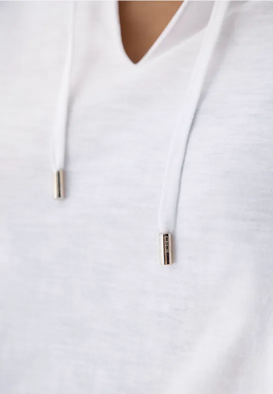 Nahaufnahme eines weißen Kapuzenpullovers mit Kordeln und Metallenden.