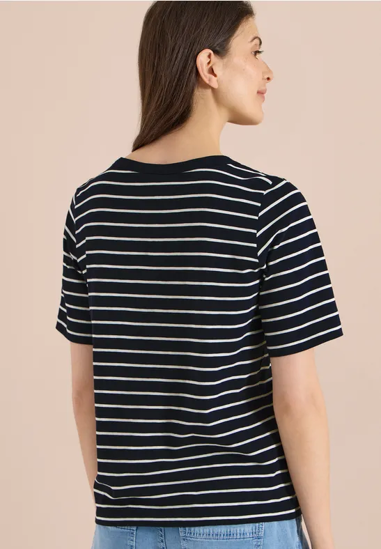 Rückenansicht einer Person in schwarz-weiß gestreiftem T-Shirt vor beigem Hintergrund.