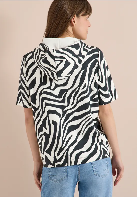 Frau von hinten in Zebra-Print-Kapuzenshirt mit kurzen Ärmeln und Jeans.