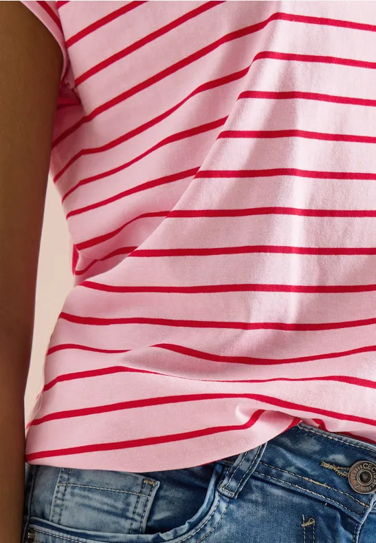 Une personne porte un t-shirt rose à rayures blanches et un jean bleu.