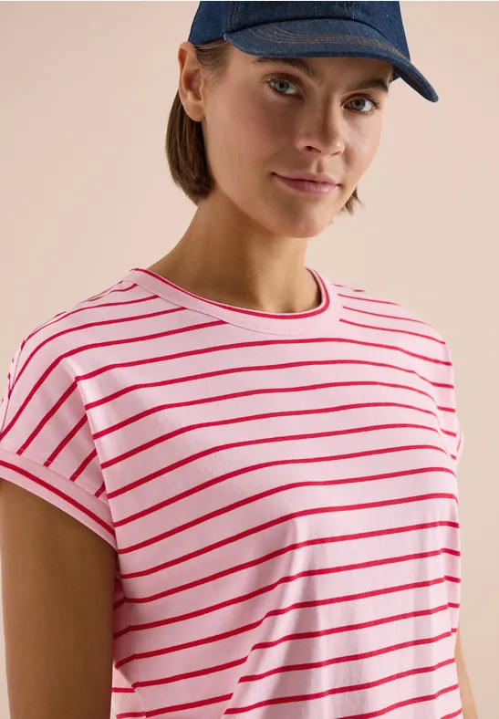 Personne en t-shirt blanc à rayures rouges et casquette bleue