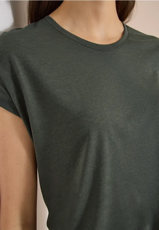 Nahaufnahme eines dunkelgrünen, kurzärmeligen T-Shirts an einer Person