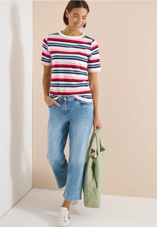 Person trägt bunt gestreiftes T-Shirt, helle Jeans und hält eine olivgrüne Tasche.