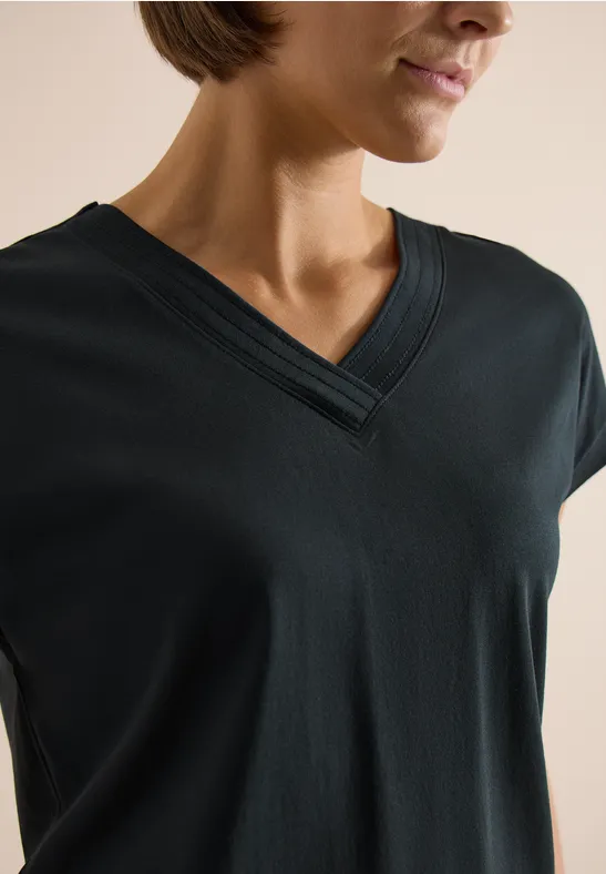 Frau trägt ein schwarzes T-Shirt mit V-Ausschnitt