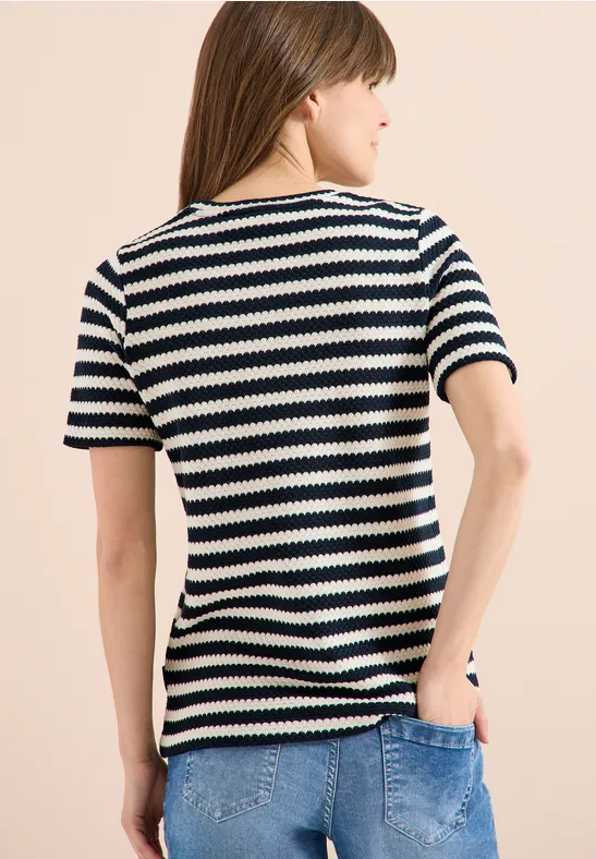 Frau von hinten, trägt schwarz-weiß gestreiftes T-Shirt und blaue Jeans.