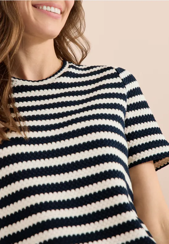 Nahaufnahme einer lächelnden Frau im schwarz-weißen, gestreiften, kurzärmeligen Strickshirt.