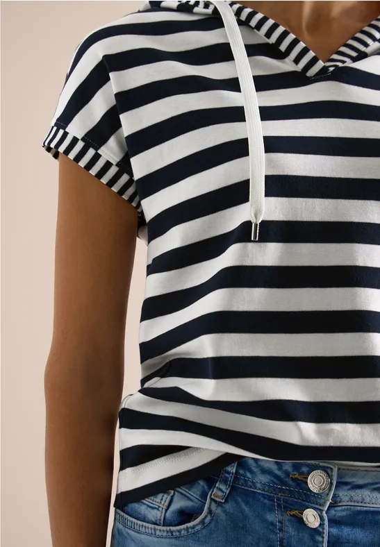 Oberkörper einer Person in blau-weiß gestreiftem Kapuzenshirt und blauen Jeans.