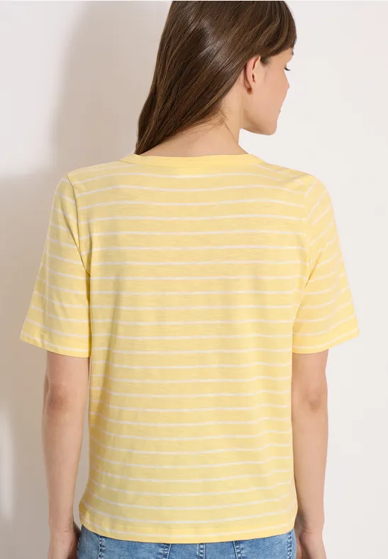 Eine Frau steht mit dem Rücken zur Kamera und trägt ein gelb-weiß gestreiftes T-Shirt.