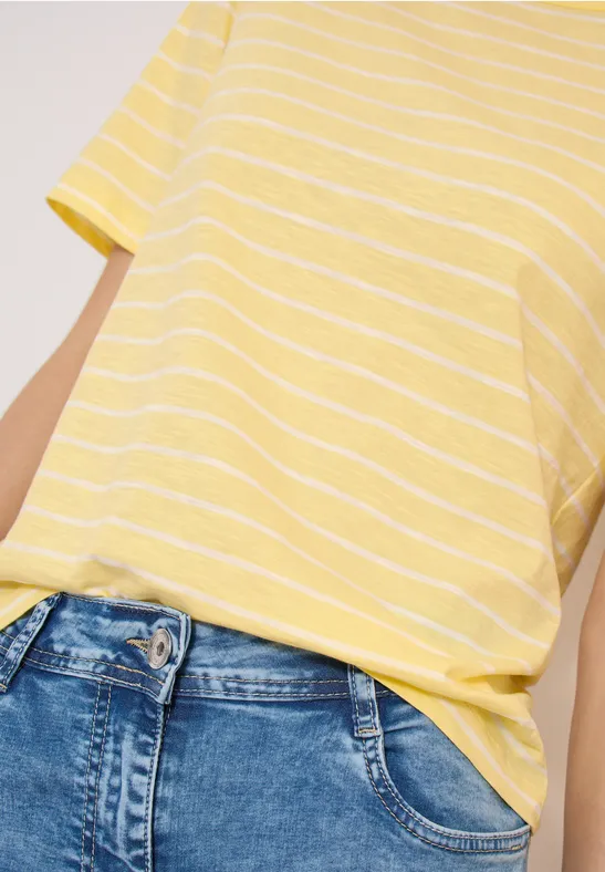 Gelb-weiß gestreiftes T-Shirt lässig in eine hoch taillierte blaue Jeans gesteckt.