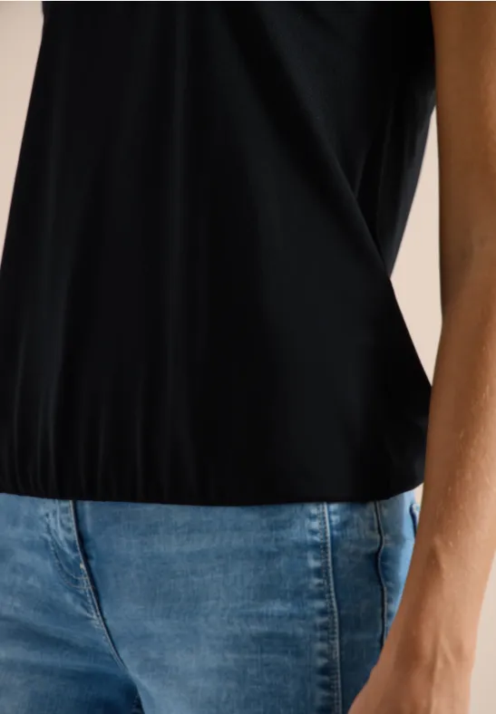 Nahaufnahme eines Oberkörpers mit schwarzem Top und blauer Jeans.