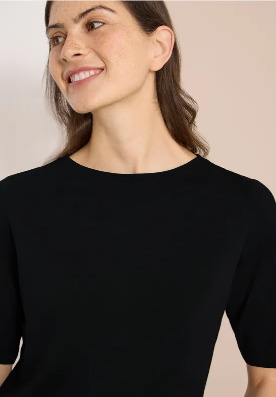 Frau in schlichtem schwarzen T-Shirt mit Rundhalsausschnitt
