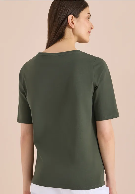 Rückansicht einer Frau in schlichtem olivgrünem Kurzarmshirt.