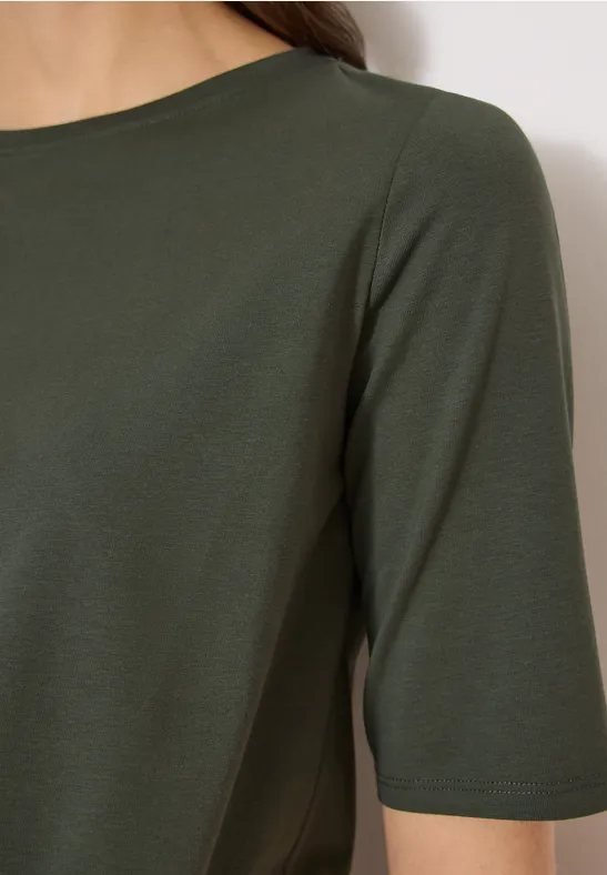 Nahaufnahme einer Person in olivgrünem Halbarmshirt.