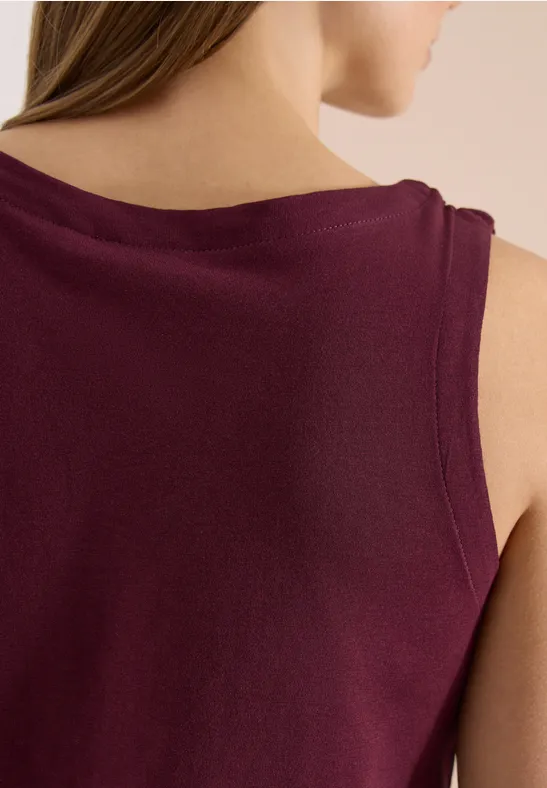 Rückenansicht einer Frau in ärmellosem, bordeauxfarbenem Oberteil