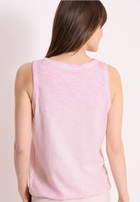 Eine Frau von hinten in einem hellrosa ärmellosen Top vor hellem Hintergrund.