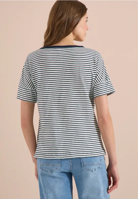 Rückansicht einer Frau in blau-weiß gestreiftem T-Shirt und Jeans vor hellem Hintergrund.