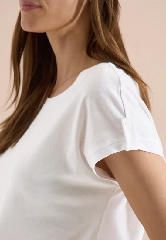 Seitliche Ansicht einer Frau in schlichtem weißen T-Shirt vor hellem Hintergrund.