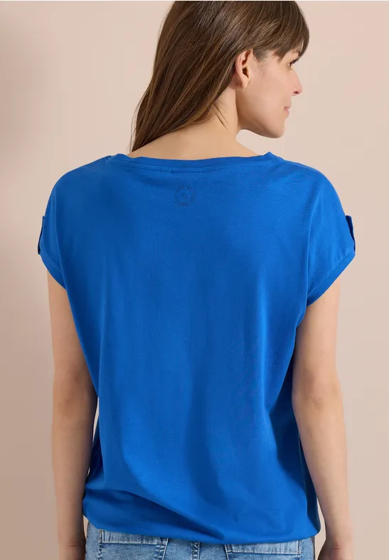 Vue de dos d'une femme portant un t-shirt bleu ample à manches courtes.