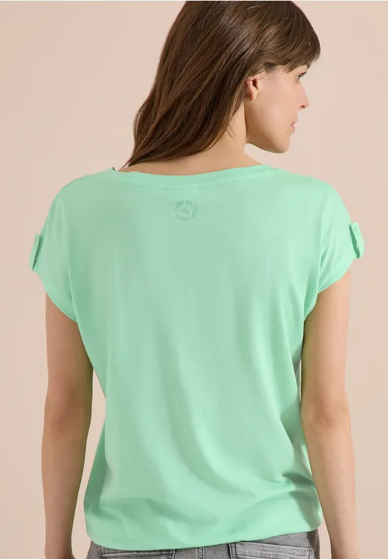 Frau von hinten in mintgrünem T-Shirt mit kurzen, locker fallenden Ärmeln, lange braune Haare.